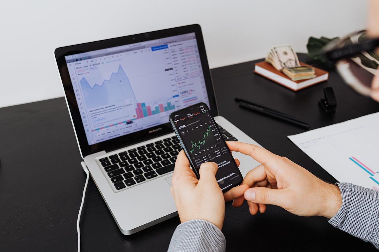 gallery-04 Person analyzing stock market data on a laptop and smartphone indoors.