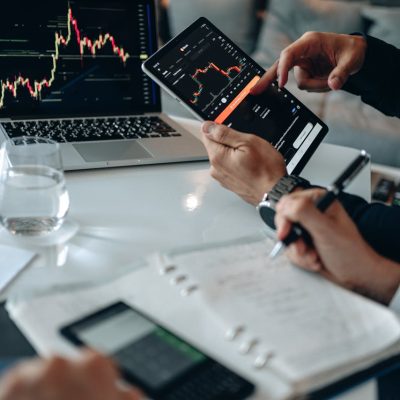 Business professionals reviewing financial charts on digital devices in a modern office setting.